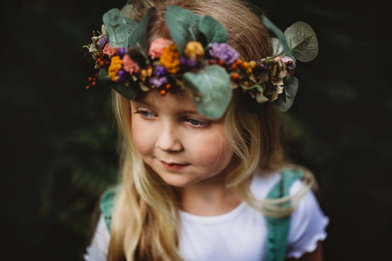 London Family Photographer, a young toddler girl stands outside with flower crown adorning her head