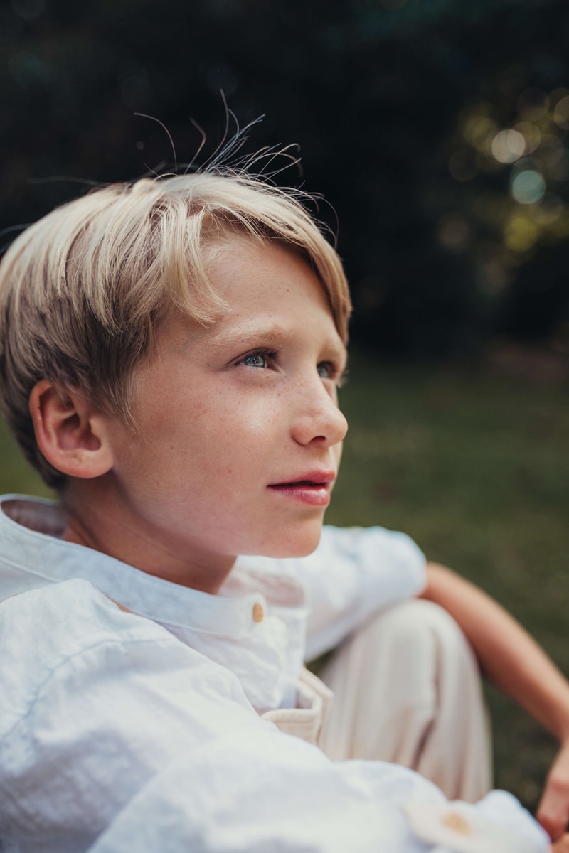 London Family Photographer, middle age boy sits pondering outdoors