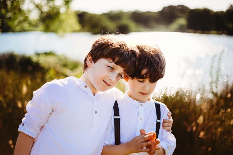 London Family Photographer, an older brother has his arm around his younger brother at the lake
