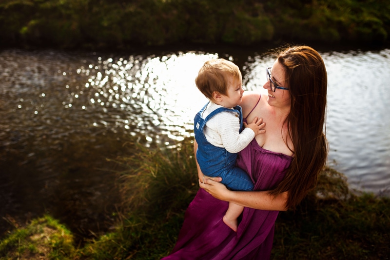 London Family Photographer, woman holds onto her baby smiling, her baby smiles back, they are by the lake
