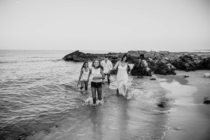 London Family Photographer, a family with two young daughters all splash through the beach waves